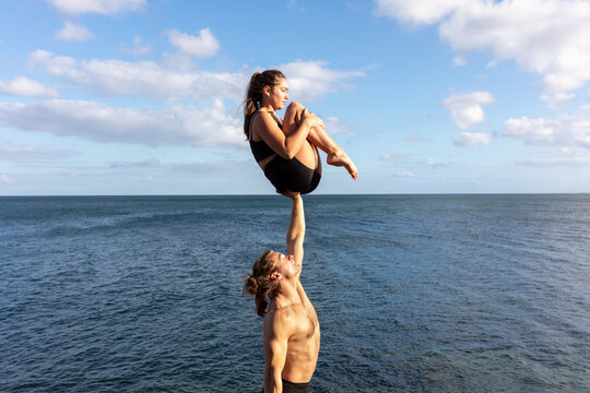 A young woman balanced on the arm of a young man.