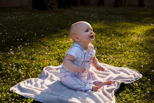 happy baby sitting on a blanket in the grass