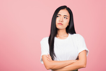Fototapeta premium Asian happy portrait beautiful cute young woman standing with crossed arms angry and mad raising fist frustrated and furious while shouting with anger isolated, studio shot on pink background