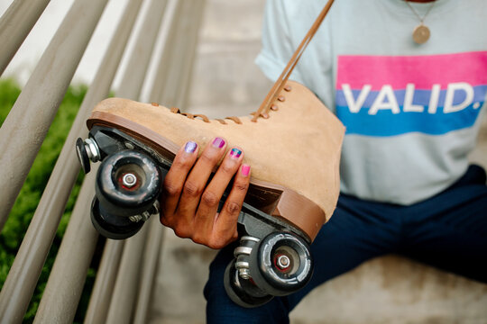 Brown rollerskate held by hand of black male wearing VALID t-shirt