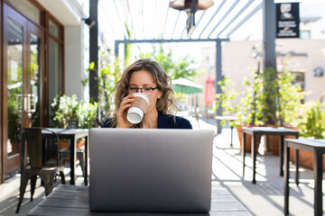 Woman Sips on Coffee While Working on her Laptop