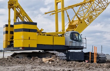Crawler crane on construction site yellow machine deck counterweight and treads, heavy duty engineering transport machinery building contractor.