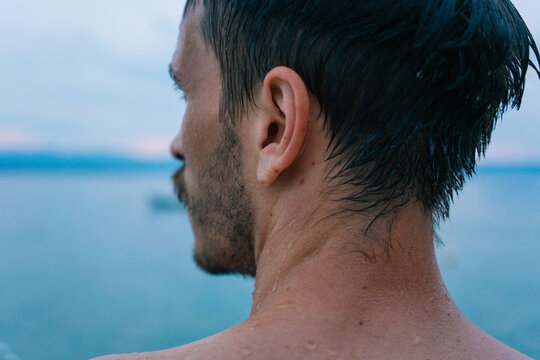 Young adult man from the back looking away after swimming