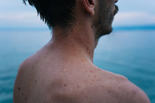 Young adult man from the back looking away after swimming