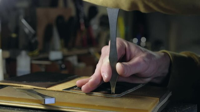 The tanner hands making holes in leather with puncher tool. Sewing wallet. Hand Made. Concept of entrepreneurship.