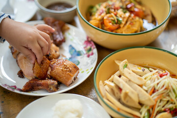 Little hand taking grill chicken from the plate.