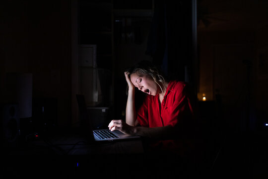 Woman Yawns While Working at Computer in the Dark
