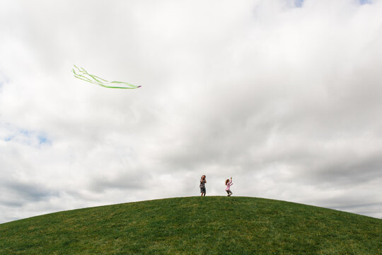 kids flying kite on a hill