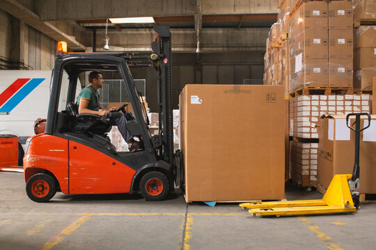 The worker transports freight using a forklift
