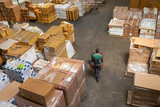 One man operates the pallet jack in a warehouse full of shipping goods