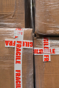 A stock photo close up of cardboard packages wrapped in the protective foil and fragile adhesive warning tape