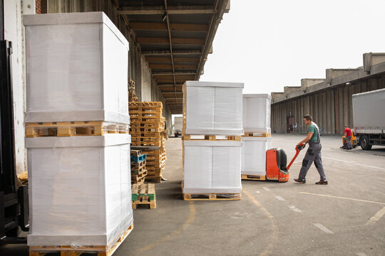 One man operates the pallet jack in a warehouse full of shipping goods