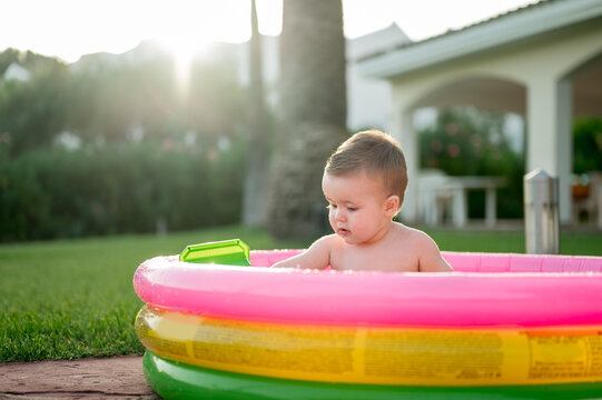 Cute Baby Playing In Inflatable Pool.