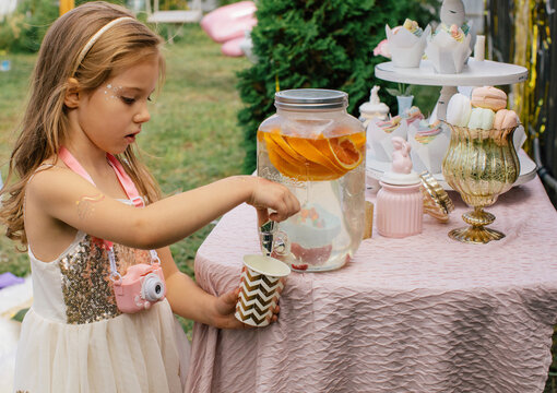 Cute girl filling cup with щкфтпу lemonade