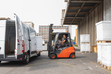 The worker transports freight into a van using a forklift