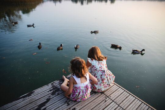 Little girls sitting on the dock watching the ducks
