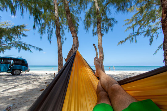Unrecognizable man resting on hammock on beach