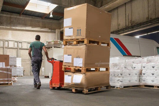 One man operates the pallet jack in a warehouse full of shipping goods