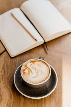 Coffe latte with latte art an notebook on top of table