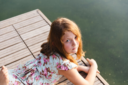 Little girl lying on a wooden pier on the lake