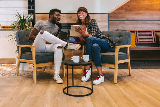 Multi-ethnic Couple Talking In An Office While Sitting By A Fire