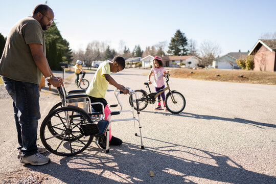 Father helps son with broken leg and walker out of wheelchair