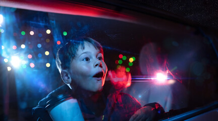 Young boy looking out the car window at christmas lights in amazement