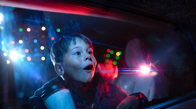 Young boy looking out the car window at christmas lights in amazement