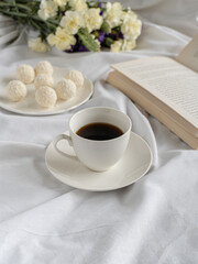  Coffee,chocolate,book and flowers on the bed. Self care 