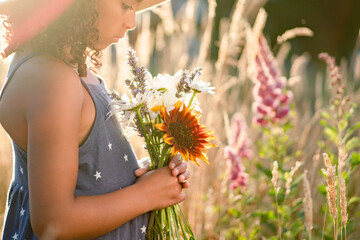 Profile of girl in straw hat and sundress at golden hour