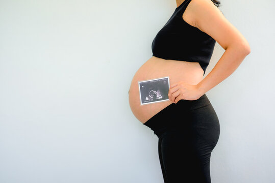 Asian pregnant woman show with ultrasound baby on white background