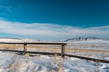 old part of the fence in the steppe in winter against the background of the mountain