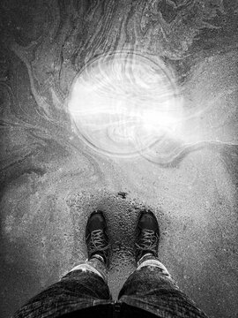 Man's legs with a sewer flooded with water.