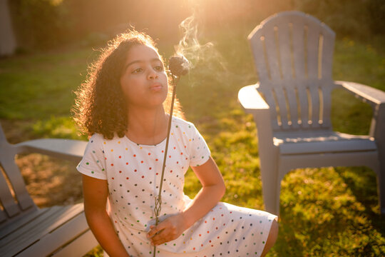 Curly haired girl blows on smoking marshmallow