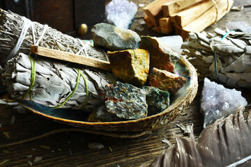 A close up image of sage smudge sticks and healing crystals in an abalone shell.