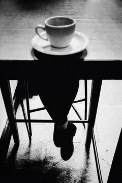 A cup of coffee with woman's legs.