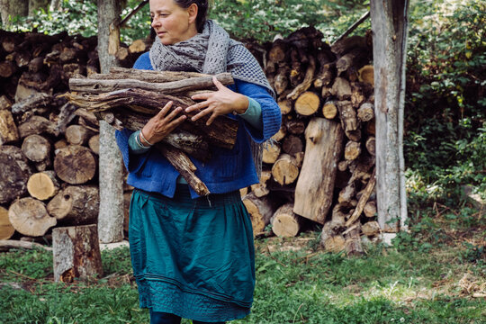 mature woman carrying wood for burning