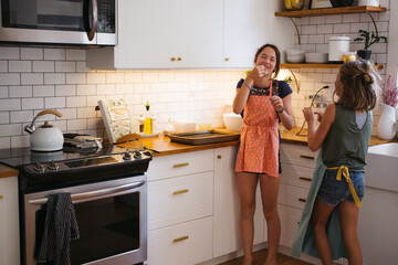 Two sisters having fun baking cookies together in a modern kitch
