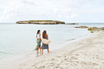Smiling friends walking along a sandy beach