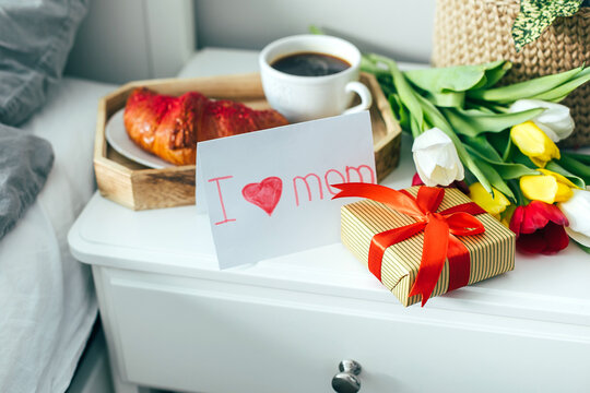 Children card on Mother's day Holiday. Tasty breakfast, cup of coffee, gift box and spring flowers.