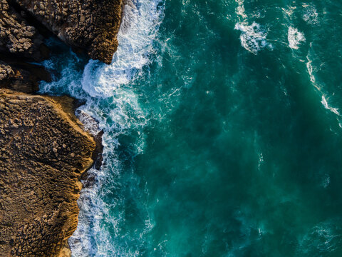 top view of ocean wave and rock, blue sea background