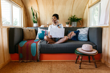 A young woman working from home on the couch using a laptop.