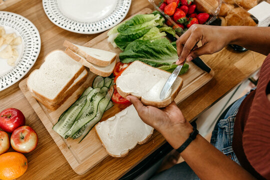 A birds eye view of a person making a homemade sandwich and spreading mayo on bread.
