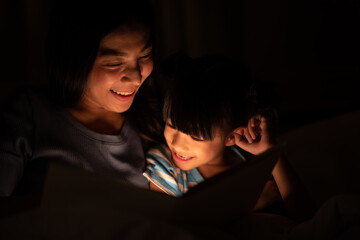 Little girl looking and reading a homework on the book at home with her mother, She has her head on...