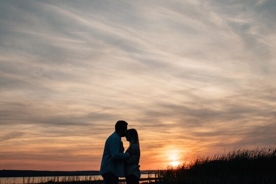 Silhouette of lovers by sunset sky