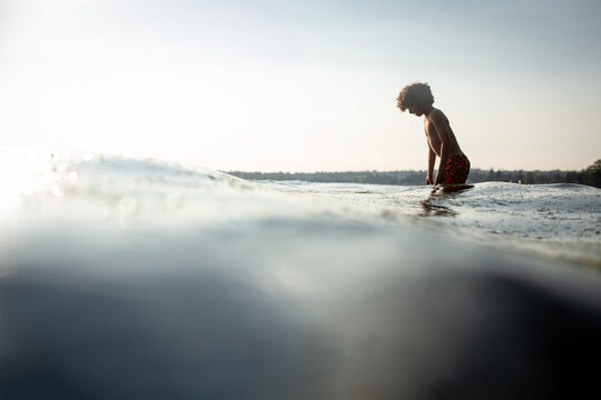 Water level partial silhouette curly haired boy in ocean