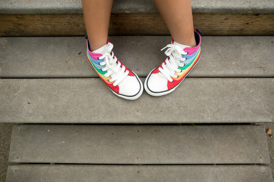 Top down view of child in rainbow shoes