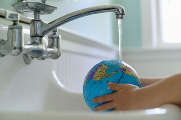 Child Washing Globe in Sink