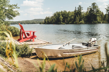 Red chair and boat sitting by a lake