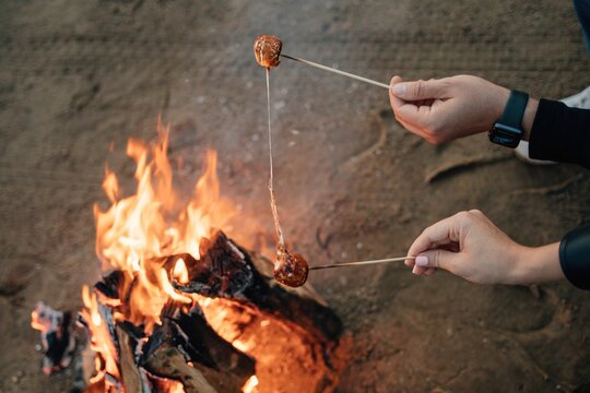 Couple toasting marshmallow over bonfire
